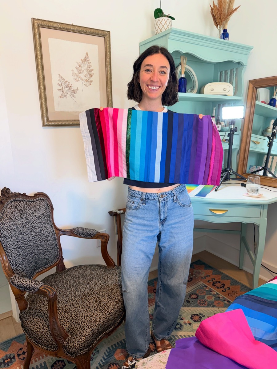 Woman holding up a fan of color analysis swatches from pink through blue